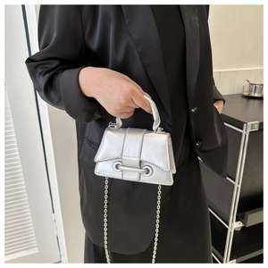 Gros plan d'un sac bandoulière argenté métallisé avec chaîne et structure trapézoïdale
