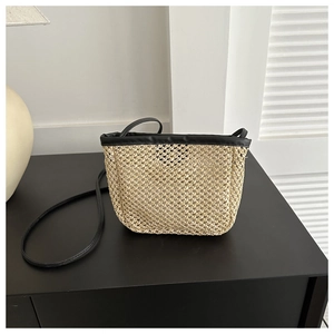 Detail of minimalist straw bucket bag showing woven texture and black faux leather trim