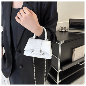 White glossy mini chain bag with metallic buckle detail on black blazer outfit