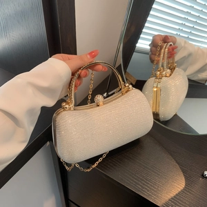 Sparkling champagne gold evening clutch bag with round metal handle and rhinestone closure