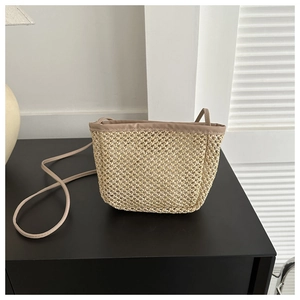 Detailed close-up of straw woven bucket bag showing natural texture and leather trim