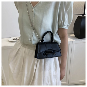 Detailed view of a structured black mini chain bag worn with a summer outfit
