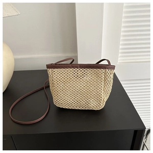 Close-up of beige woven bucket bag with contrast dark brown leather shoulder strap detail