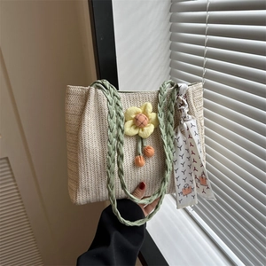 Summer straw tote bag with green handles and yellow sunflower charm for beach vacation