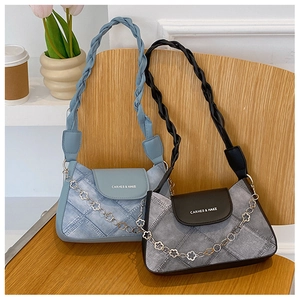 Detailed close-up of denim shoulder bags with woven handles and golden flower chains