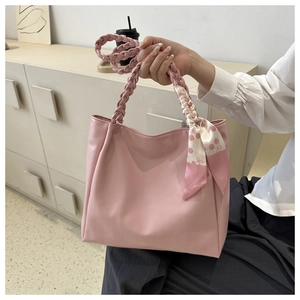 Detail of light pink tote bag featuring a woven handle and floral silk scarf accessory