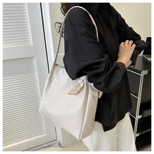 Detail of beige houndstooth tote bag featuring woven texture and decorative floral silk scarf