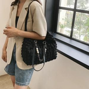 Black bubble texture tote bag with pearl chain strap worn by model in soft light