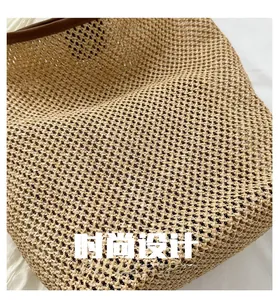Gros plan du cabas en paille tressée beige avec bordure en cuir marron et texture filet