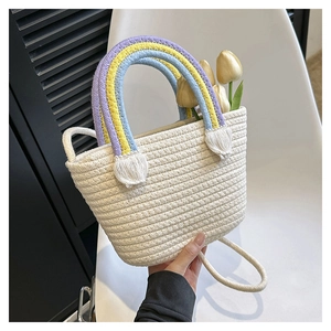 Detail der Stroh-Eimertasche mit Regenbogen-Webgriff, weißen Quasten und schmalem Schultergurt