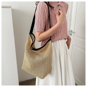 Texture détaillée du sac fourre-tout en paille tissée avec bretelles noires contrastées