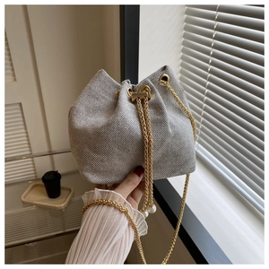Détail du sac seau tissé avec chaîne dorée et cordons ornés de perles décoratives
