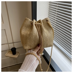 Détail du sac seau tissé avec motif à chevrons, chaîne dorée et cordons en perles