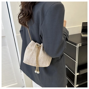 Détail du sac seau tissé avec cordon à perles et bandoulière chaîne dorée