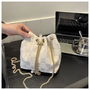 Détail du sac seau tissé crème avec texture à carreaux et pendentif perle élégant