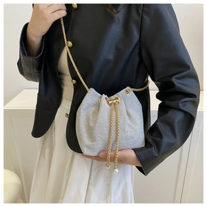 Détail du sac seau tressé argenté avec cordon perle et bandoulière chaîne dorée sur mannequin