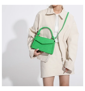Detail einer hellgrünen Handtasche aus gewebtem PU-Leder mit Klappe und rundem Griff