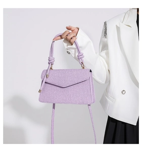 Detail der lila geflochtenen PU-Handtasche mit goldenen Beschlägen und modischem Griff