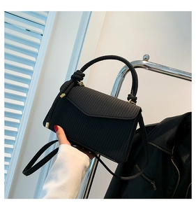 Nahaufnahme der schwarzen Handtasche mit Fischgrätmuster und eleganten goldenen Beschlägen