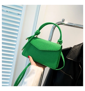 Detailansicht der leuchtend grünen geflochtenen Handtasche mit dreieckiger Klappe
