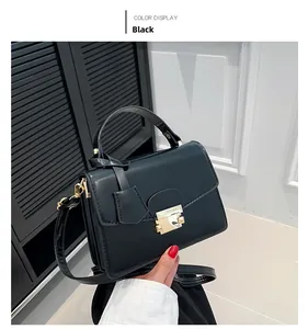 Detail van zwarte crossbody tas van glad imitatieleer met gouden vierkante sluiting
