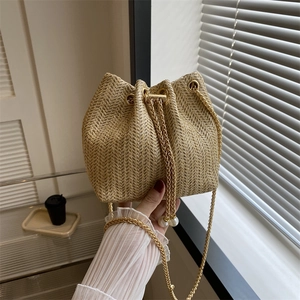 Sac seau chic en paille tissée avec bandoulière dorée et perles décoratives
