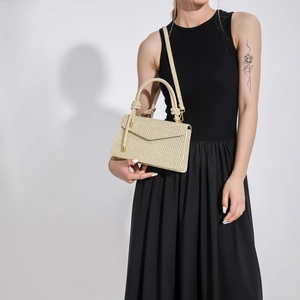 Modische beige gewebte PU-Handtasche mit Schultergurt, getragen von einem Modell in Schwarz