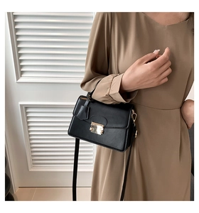 Modieuze zwarte leren crossbodytas met gouden gesp gedragen door een vrouwelijk model