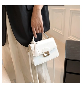 Detailopname van witte leren crossbodytas met gouden gesp op een elegant model
