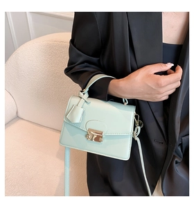 Detailopname van lichtgroene crossbodytas met gouden gesp en glad kunstlederen vlak