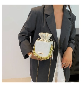 Close-up of white pebble leather mini bag with gold chain strap and drawstring closure