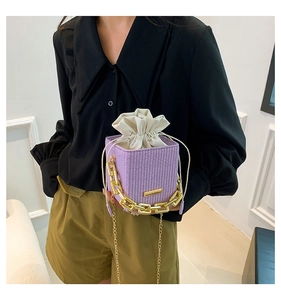 Detail of purple woven bucket bag with cream drawstring liner and chunky gold chain handle