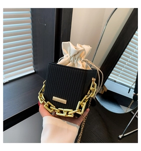 Detail of black woven box bag featuring gold chain handle and white drawstring liner