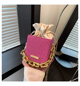 Detail of bright pink woven bucket bag featuring gold chain handle and white drawstring