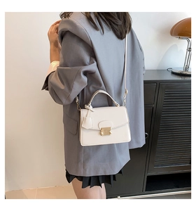 Crèmewitte lederen crossbody tas met gouden gesp, gedragen door een model in outfit