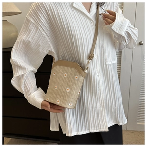 Détail de la broderie marguerite sur sac seau en paille avec bandoulière en cuir