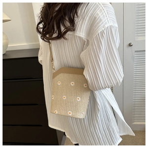 Détail de la broderie marguerite sur le sac seau en paille kaki avec bord en cuir