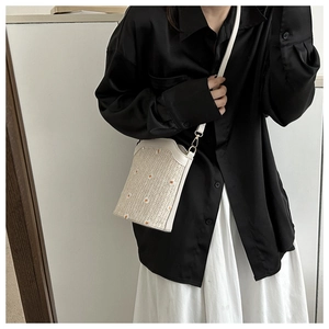Détail d'un sac seau en paille avec broderie marguerite élégante et fine bandoulière