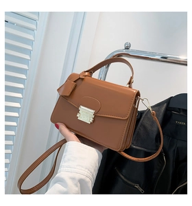 Detail van karamel PU-leren handtas met goudkleurige sluiting en afneembare riem