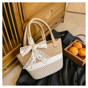 Detailed texture of two-tone woven straw bucket bag featuring a large white lace bow