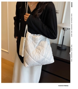Close-up of white quilted tote bag featuring metal chain strap and matching small pouch