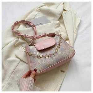 Detail der rosa bedruckten Handtasche mit dekorativer goldener Blumenkette und Webriemen