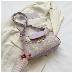 Makro-Detail der lavendelfarbenen Schultertasche mit Goldkette und Blumenanhänger