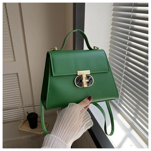Detail of green leather handbag featuring golden T-shaped twist lock and top handle