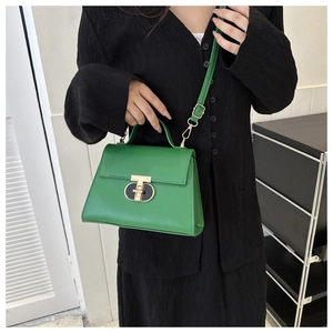 Detail of green PU leather crossbody bag featuring a striking gold T-shaped metal clasp