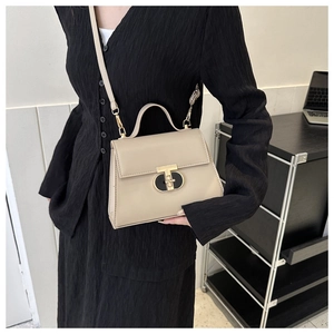 Chic beige PU leather handbag with gold T-lock shown as a crossbody bag on model