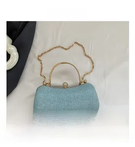 Close-up of light blue textured evening bag with gold handle and crystal clasp on white fabric