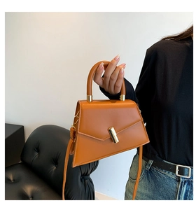 Dettaglio di una borsa a trapezio marrone con fibbia in metallo oro e manico in pelle