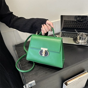 Structured grass green PU leather handbag with gold metal lock on a professional desk
