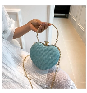 Detail of light blue heart-shaped evening bag with glitter texture and gold ring handle